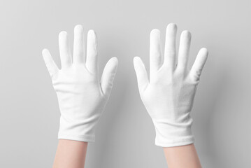 Fototapeta premium Pristine Care: Hands in White Gloves on Grey Background