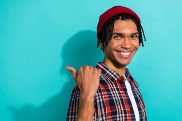Photo of positive optimistic guy with dreadlocks wear plaid shirt indicating at sale empty space isolated on turquoise color background
