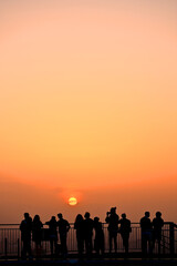 silhouette tourist group watching gold lighting sunset or sunrise sky background on skyscaper building