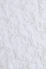 Vertical look of chic embroidered white satin fabric. flowers embroidered with beads and sequins. Wedding festive background
