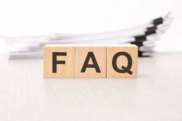 FAQ letters on wooden cubes. the background is a white business papers. finance concept