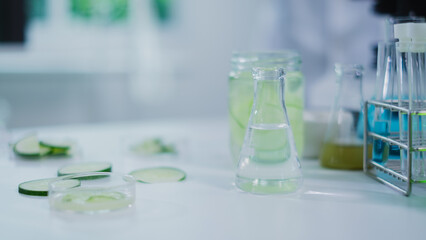 Cosmetic, skincare and treatment laboratory. Laboratory equipment and fresh cucumber slices in glassware, test tube or beaker. Concept of Serum, gel or cream essential experiment. Product advertise.