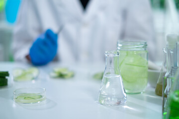 Cosmetic, skincare and treatment laboratory. Laboratory equipment and fresh cucumber slices in glassware, test tube or beaker. Concept of Serum, gel or cream essential experiment. Product advertise.