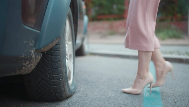 Car accident. Closeup on woman in the city with smartphone near car with flat tire.