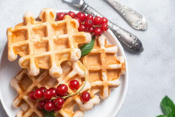Belgian waffles with red currants in a bowl