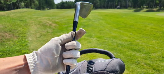 Female hand of golfer in glove holds bag with golf clubs