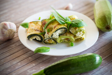 cooked zucchini rolls with cheese filling inside, in a plate