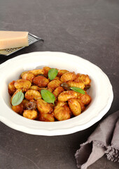 Traditional Italian potato dumplings with tomato sauce, fresh basil and parmesan cheese on a brown background. Top view.