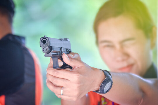 Young woman in shooting range pointing forward with gun