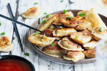 Plate of golden fried Chinese dumplings, also known as Pot Stickers, with sweet and sour sauce....