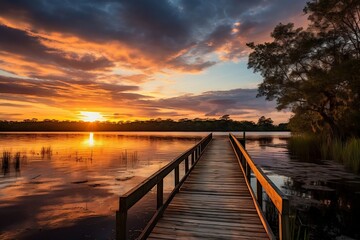 Obraz na płótnie Canvas A wooden walkway leading to a sunset over a marsh. AI