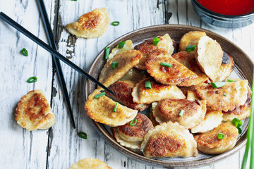 Overhead view of a plate of golden fried Chinese dumplings, also known as Pot Stickers, with sweet and sour sauce. 