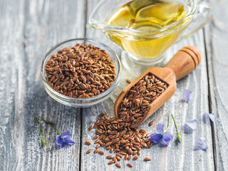 Flax seeds and flax oil. Brown linen seeds and flaxseed oil on old gray wooden background. Copy space