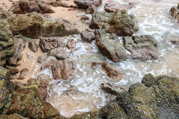 Stones on the beach in surf water, tropical sea.