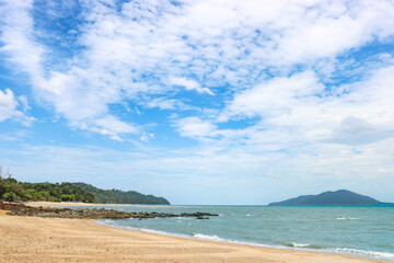 Obraz premium Tropical sandy rocky beach with clear clear blue water under a blue sky with cirrus clouds.