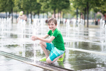 happy boy playing in dry fountain in summer