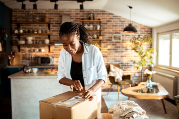 Young woman opening up the package she received in the mail at home in th ekitchen