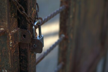 selective focus of a padlock and chain on a rusty metal doorgate