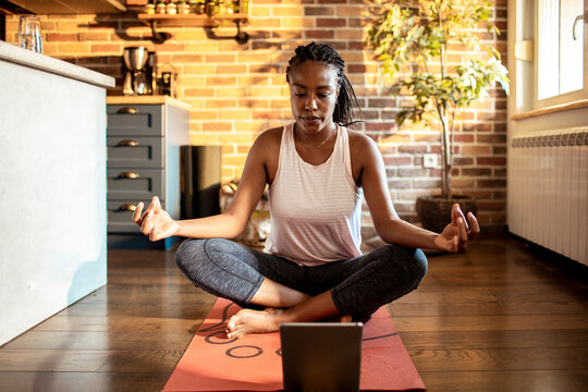 Young woman doing yoga and exercising at home in the living room