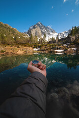 A man with a compass in his hand in the high mountains against the backdrop of a clear lake. Travel concept. landscape photography