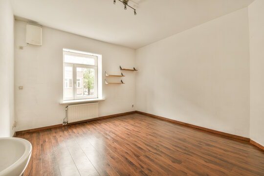 an empty room with wood flooring and white paint on the walls, there is a bathtub in the corner