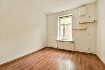 an empty room with wood flooring and white paint on the walls, there is a window in the corner