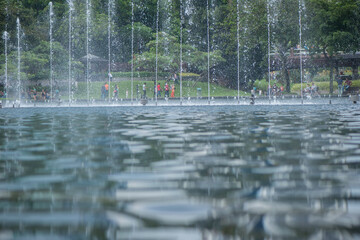 Fountain complex line with walking people recreation area in public city  tropical park.