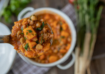 Chickpea stew with sweet potatoes and meat on a ladle