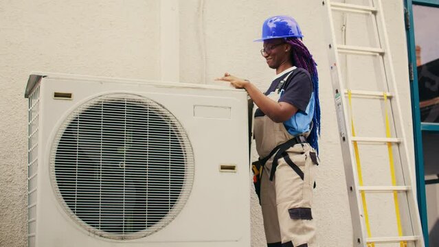 Efficient repairman starting work on defective air conditioner, using handheld drill to disassemble condenser metal coil panel. Experienced mechanic dismantling hvac system to check for dirt