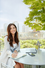 Portrait of smiling attractive female freelancer sitting at workplace, remote job outdoors