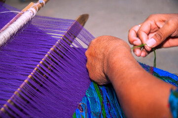 Detail of woman's hands weaving typical dyed cotton clothes in Guatemala, making clothes as a means of income from tourism. - 620625254