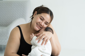Happy smiling Asian young mother take care and hugging her newborn on hands with kindness. family,...
