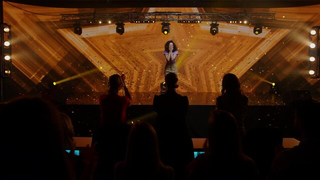 Judges Press The Golden Buzzer To Send A Contestant To A Show Finale, The Lights Changing To Gold, Young Woman Dancer Talent Is Happily Surprised. Television Style Broadcast Talent Show