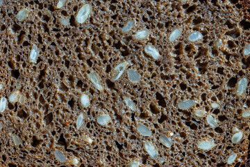 Abstract background or texture homemade black bread with sunflower seeds, closeup, top view, macro