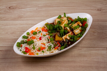 paneer chilli rice in white plate on wooden background