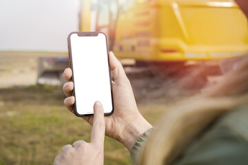 Construction Management in Action: Person Holding White Screen Smartphone on Site