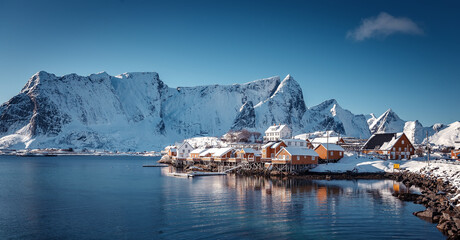Beautiful winter view on Sakrisoy village with perfect reflected at sunny day. Incredible winter scenery with traditional fisherman cabins and snowy peaks in the Lofoten Islands. Norway, Scandinavia.