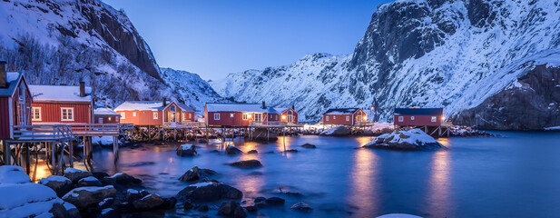 Amazing winter seascape. Nusfjord authentic fishing village with traditional red rorbu houses in winter during sunset. Lofoten islands, Norway. Typical north scenery of Lofoten islands. Norway - obrazy, fototapety, plakaty