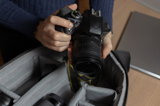 Young woman checks if her camera is in order so she can put it in her backpack.