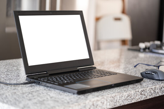 ordenador negro portátil abierta con pantalla en blanco sobre barra de cocina
