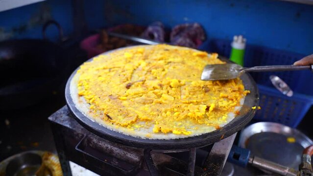 Spreading hot chili and other spices with potato stuff on famous Indian food dosa while making dosa on a hot gas stove, slow motion stock footage