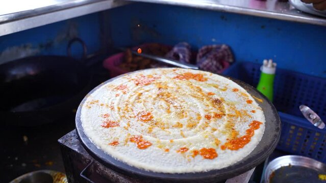 Indian Dosa street food slow motion stock footage Spreading hot chili on famous Indian food dosa while making dosa on a hot gas stove, slow motion stock footage
