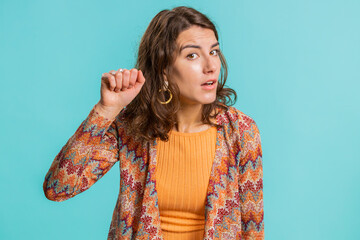 Knock-knock who is there. Excited young woman knocking door gesture asking who is at home, feeling embarrassed, no idea, being clueless and uncertain. Girl isolated alone on studio blue background