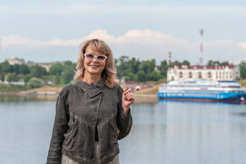 Mature adult attractive woman on the background of pier with ship and cityscape.