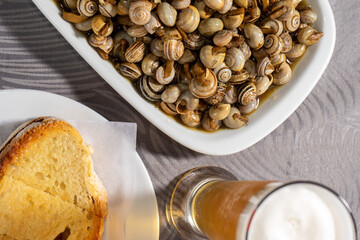 Delicious Portuguese delicacy: Snails served with crispy toast and accompanied by a refreshing cold beer. A quintessential snack from Portugal.