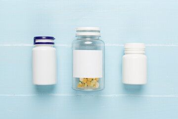 Plastic bottles with vitamins on wooden background, top view