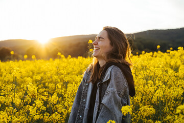 Happy Young woman in flowers field during sunset