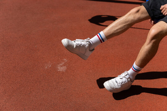 Legs and shoes of man sitting on swing in park