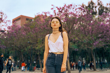 Woman in eyeglasses standing on the background of jacaranda in Mexico