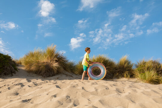 Boy rolling donut float down the dunes